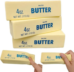Four 4oz blocks of salted butter with hands holding two of them on a white background