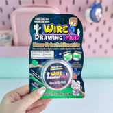 Packaged toy called 'Wire Drawing Mud' held by a hand with a pink background