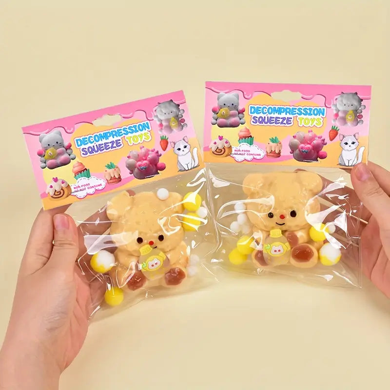 Two decompression squeeze toys in clear packaging with pink packaging featuring cartoon characters on a beige background.
