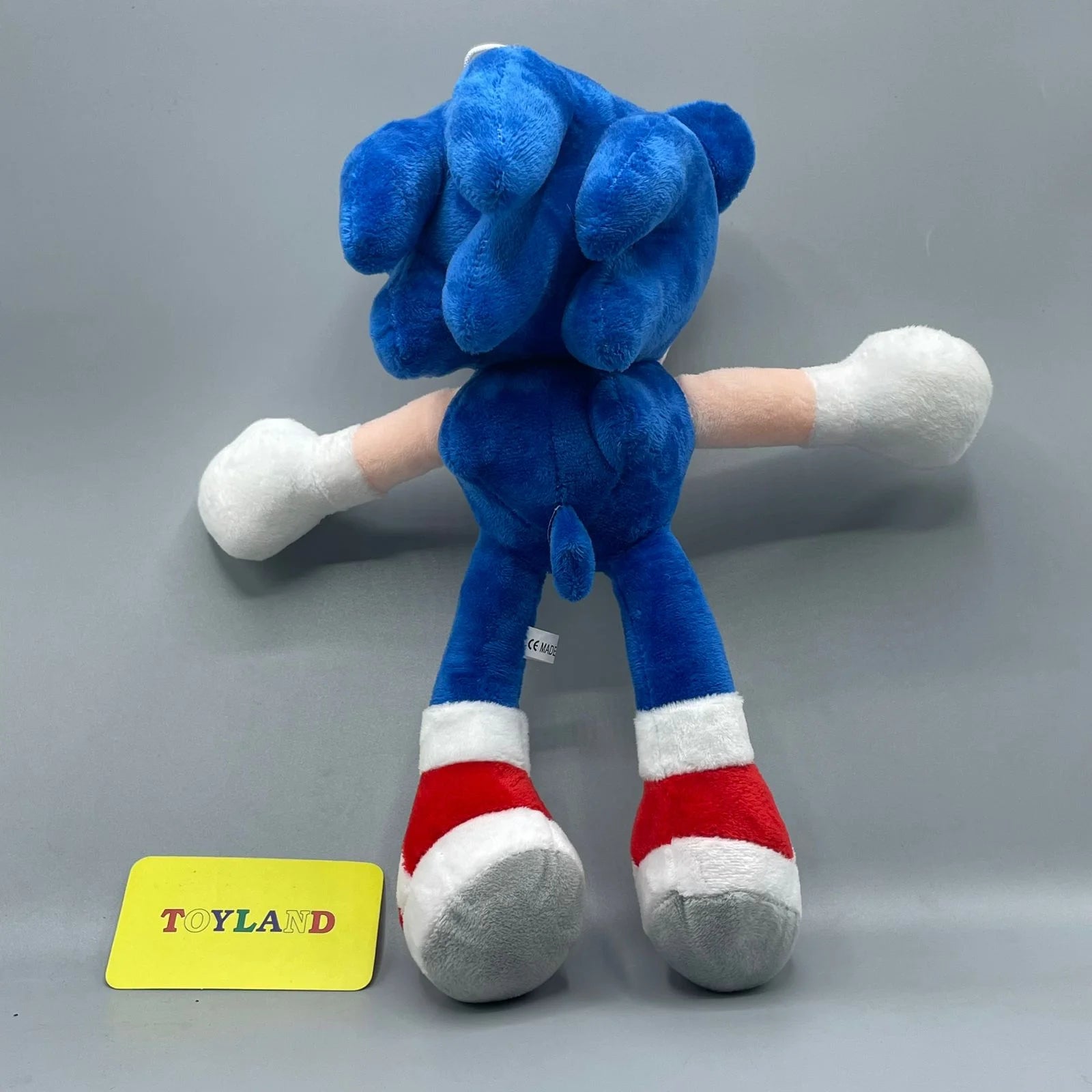 Blue plush toy with red and white accents on a gray background, featuring a 'Toyland' label.