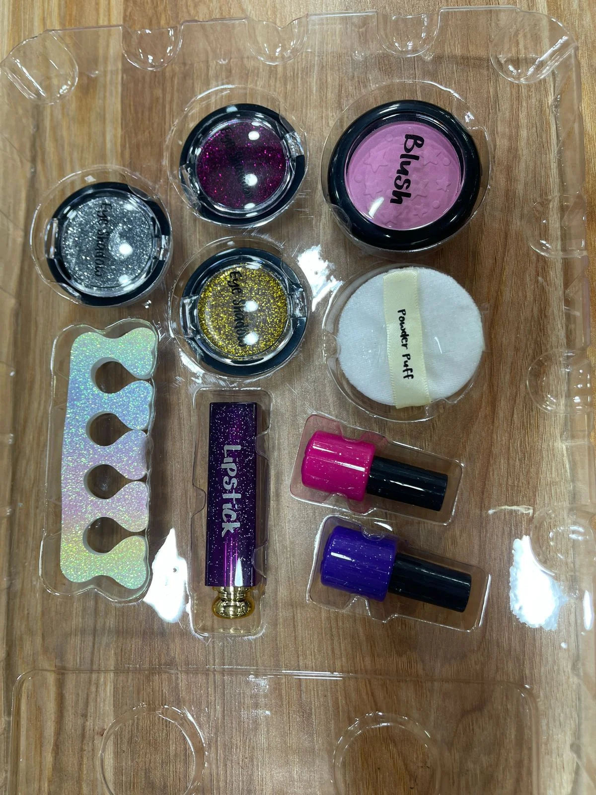 Makeup set with various items including blush, lip gloss, and nail polish on a wooden surface.