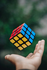 Rubik's Cube held in a hand with a blurred green background